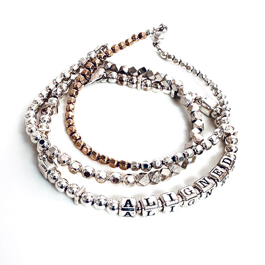 Sterling Silver Engraved Message Bracelet spelling out Aligned shown with additional sterling silver  and gold stacking  bracelets