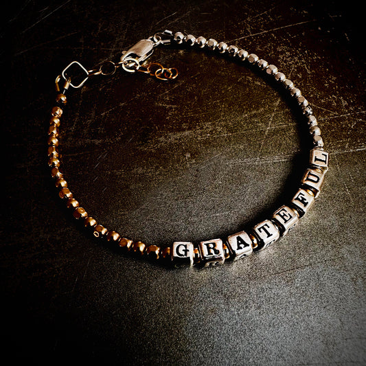Gratitude Practice Bracelet in sterling silver and 14k gold beads that spell out the words GRATEFUL