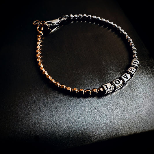 Beaded bracelet in sterling silver and 14k gold spells out the word LOVED with sterling silver letters