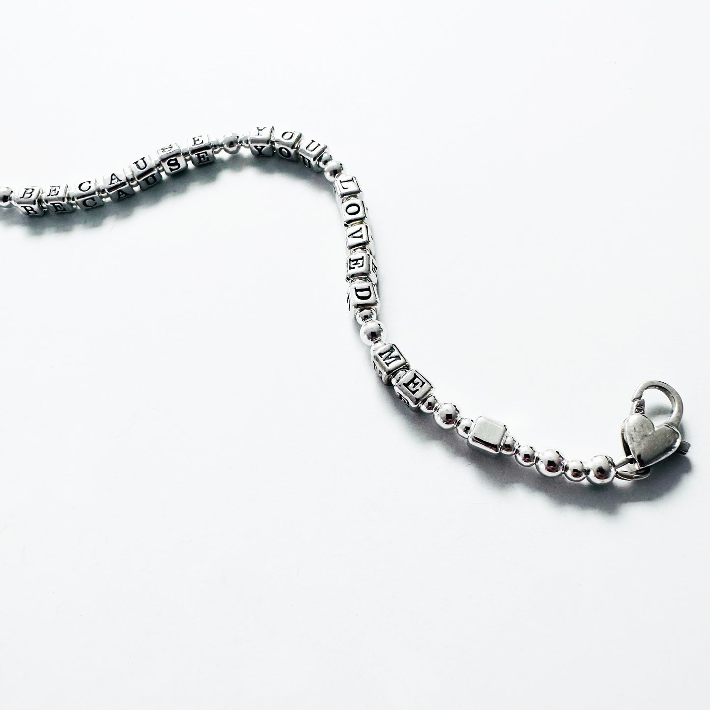Love Bracelet in all sterling silver spells out Because You Loved Me, shown with heart clasp