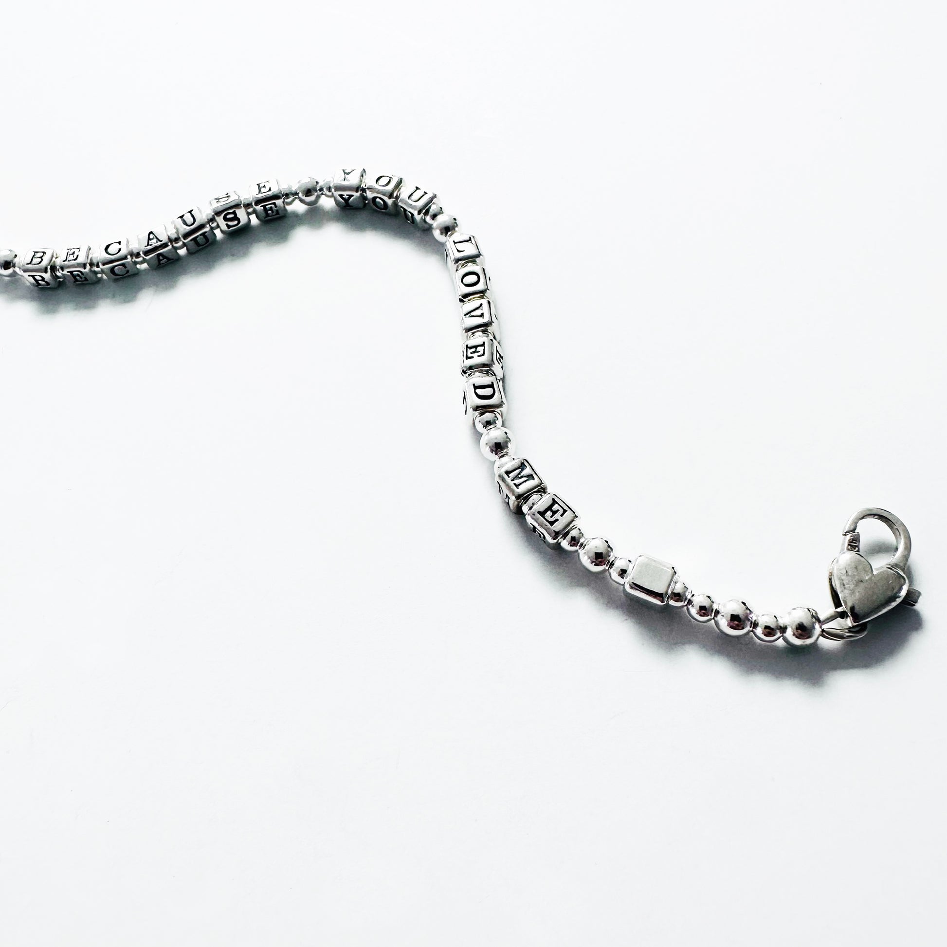 Love Bracelet in all sterling silver spells out Because You Loved Me, shown with heart clasp