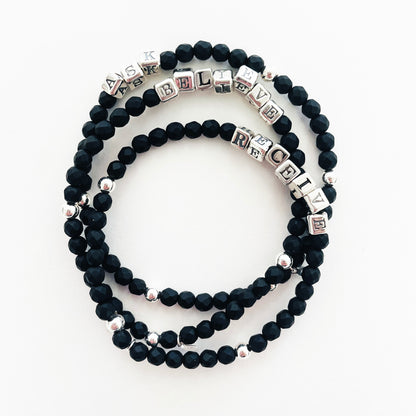 High quality sterling silver and onyx beaded elastic bracelet that spells out the word BELIEVE, shown with two additional bracelets that spell out ASK and RECEIVE