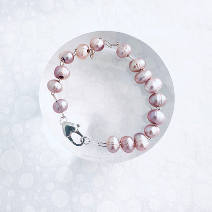 Pink pearl bracelet, where pink pearls are strung on a sterling silver chain with a heart shaped clasp