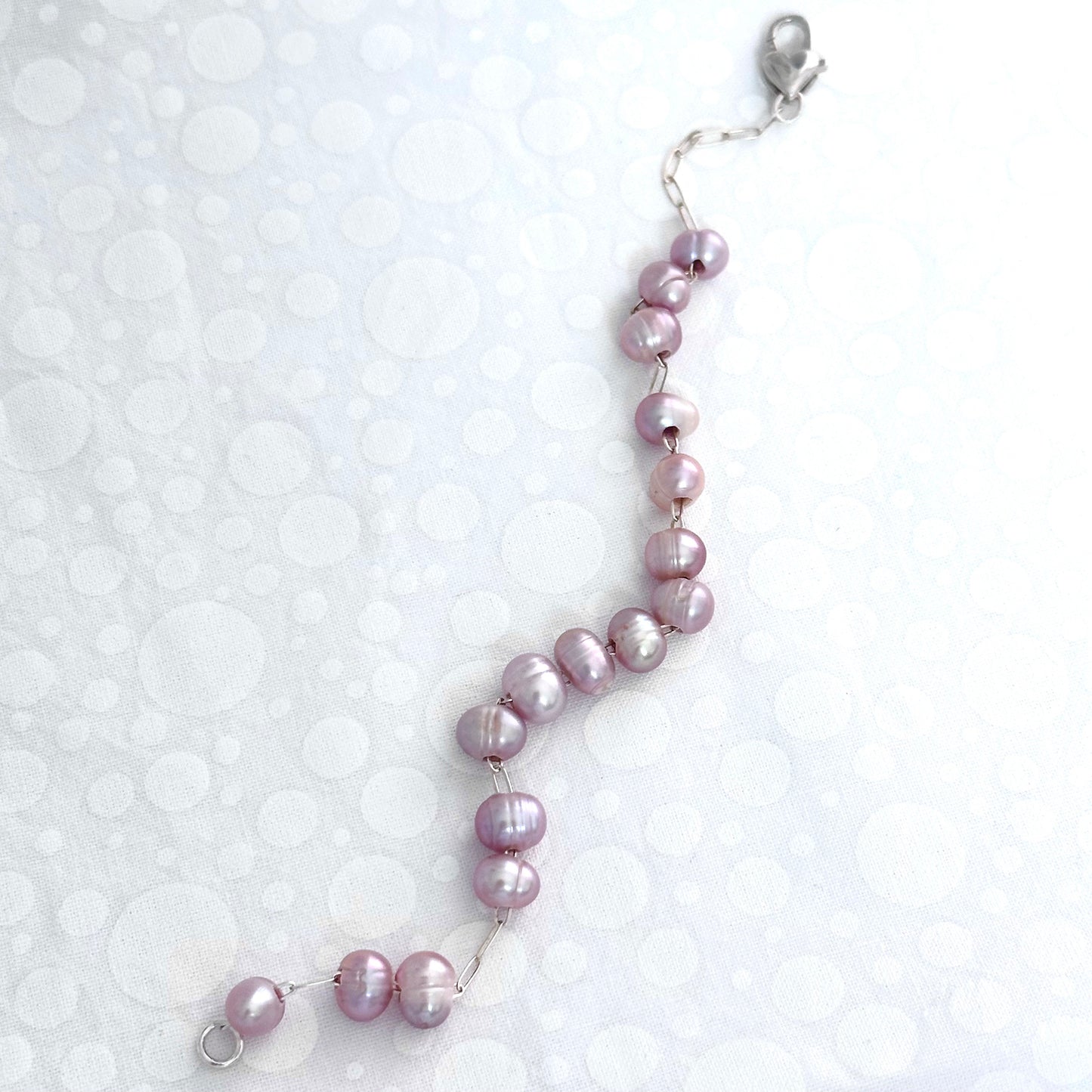 Pink pearl bracelet, where pink pearls are strung on a sterling silver chain with a heart shaped clasp