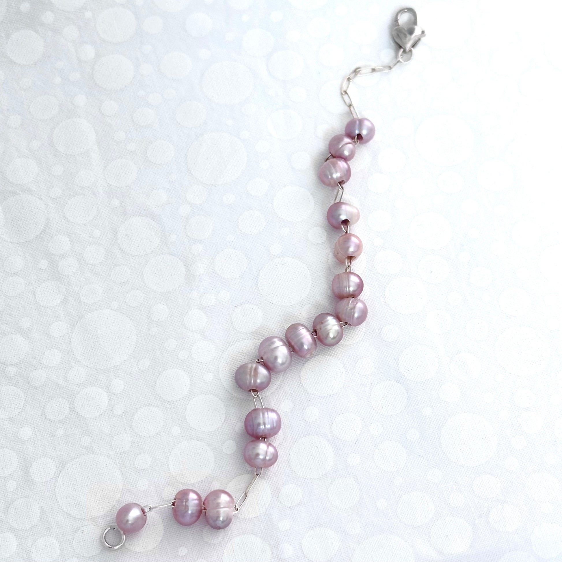 Pink pearl bracelet, where pink pearls are strung on a sterling silver chain with a heart shaped clasp