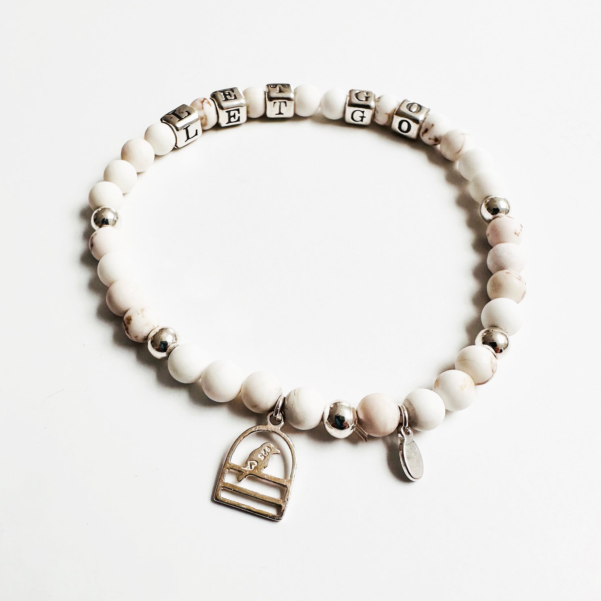 Let Go stretch bracelet in sterling silver and white howlite beads, showing sterling silver bird charm