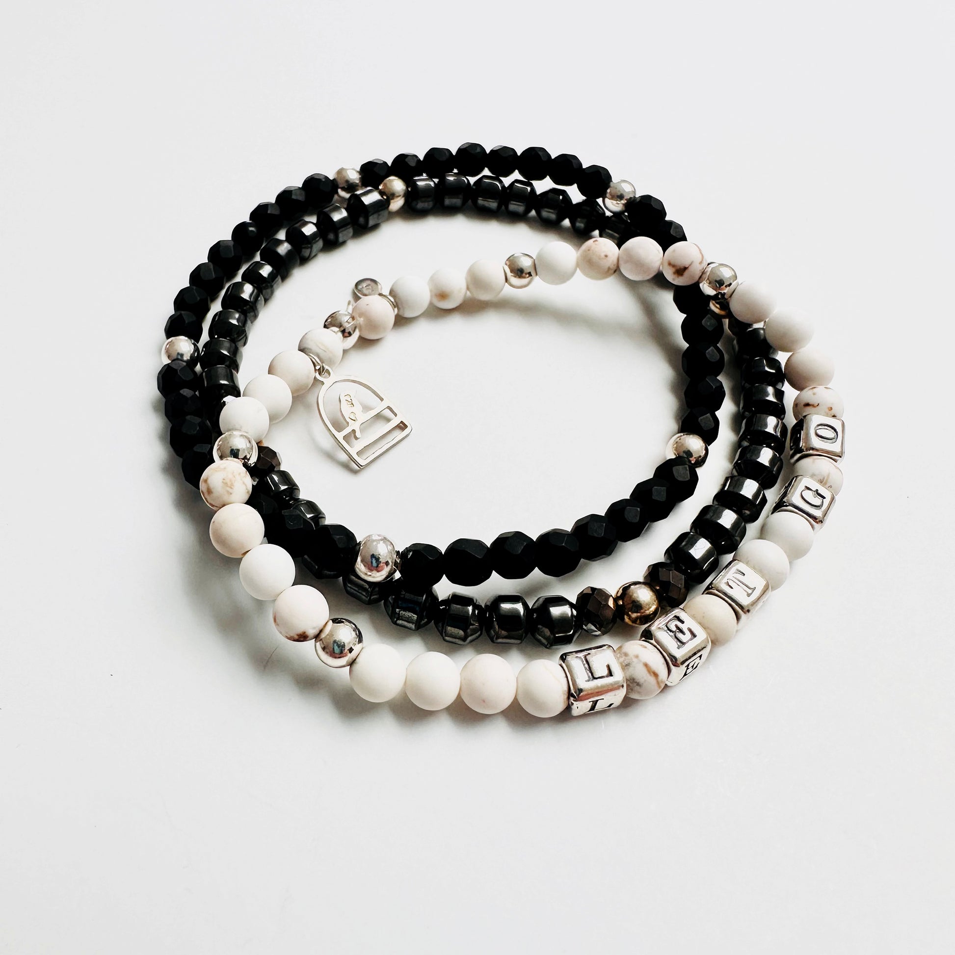 Let Go stretch bracelet in sterling silver and white howlite beads, with sterling silver bird charm and black only and hematite stretch bracelets