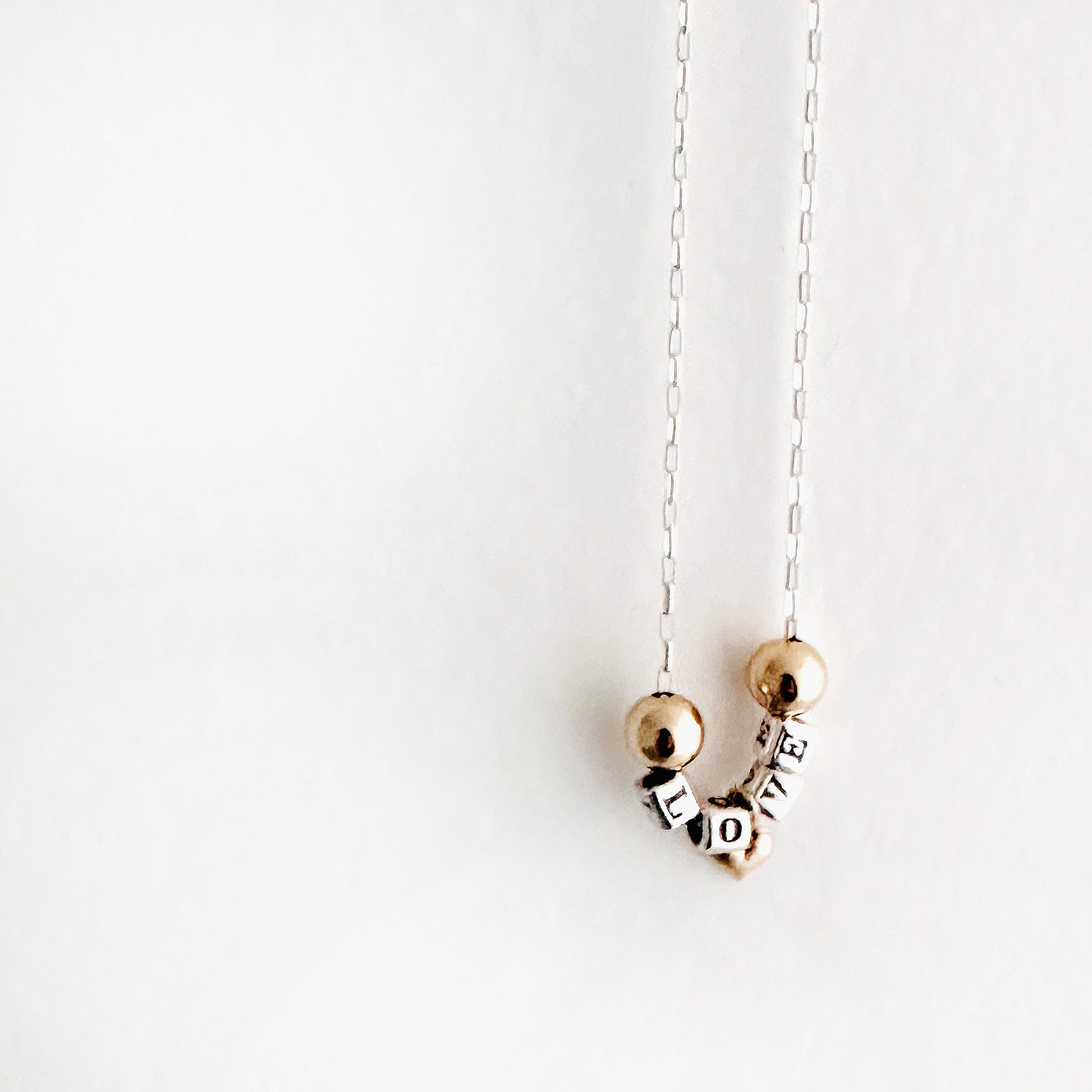 Delicate  Sterling silver and 14k gold necklace that spells out the word love in sterling silver beads