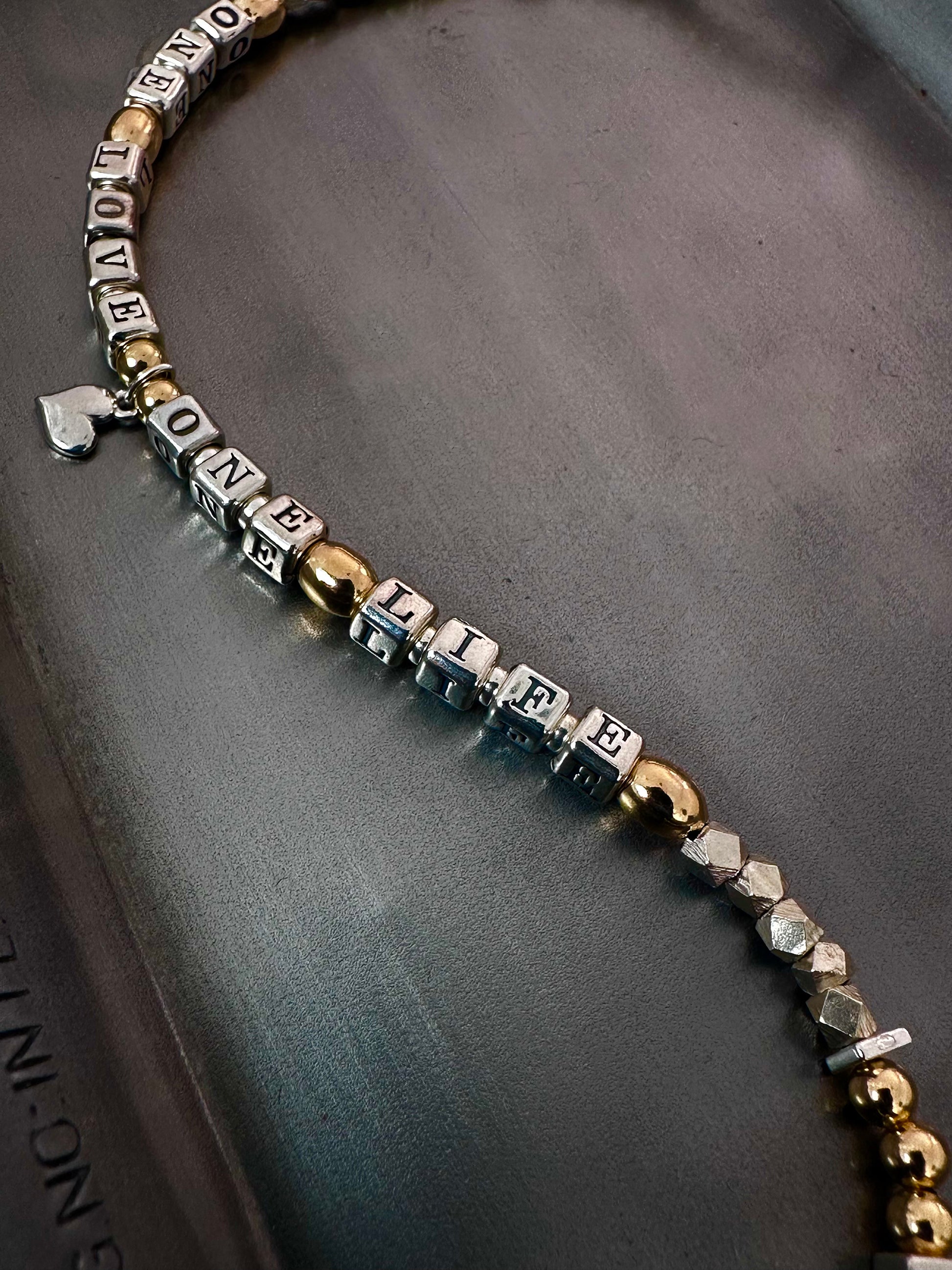 Necklace with letter beads that spell One Love One Life in sterling silver and 14k gold
