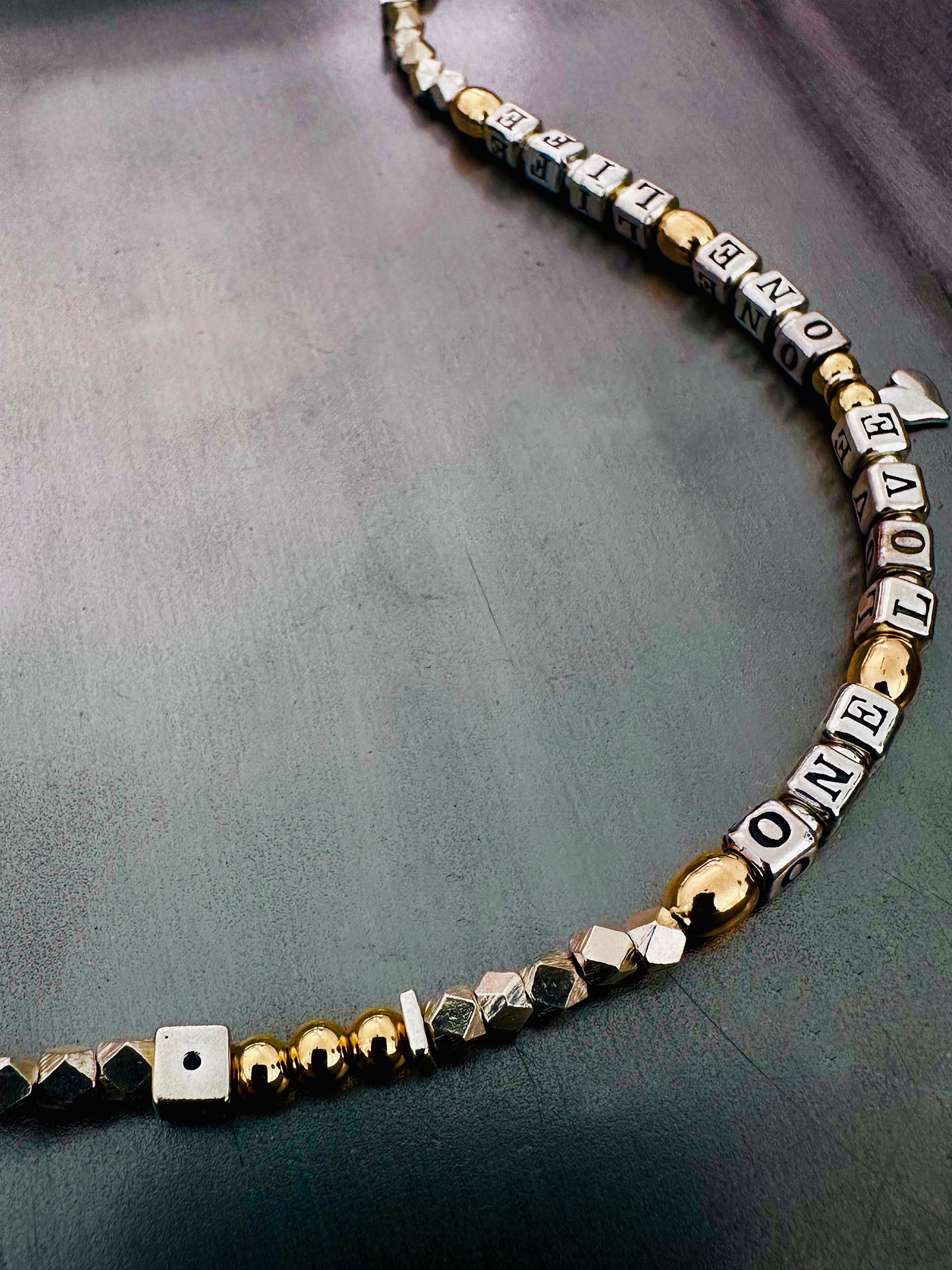 Necklace with letter beads that spell One Love One Life in sterling silver and 14k gold