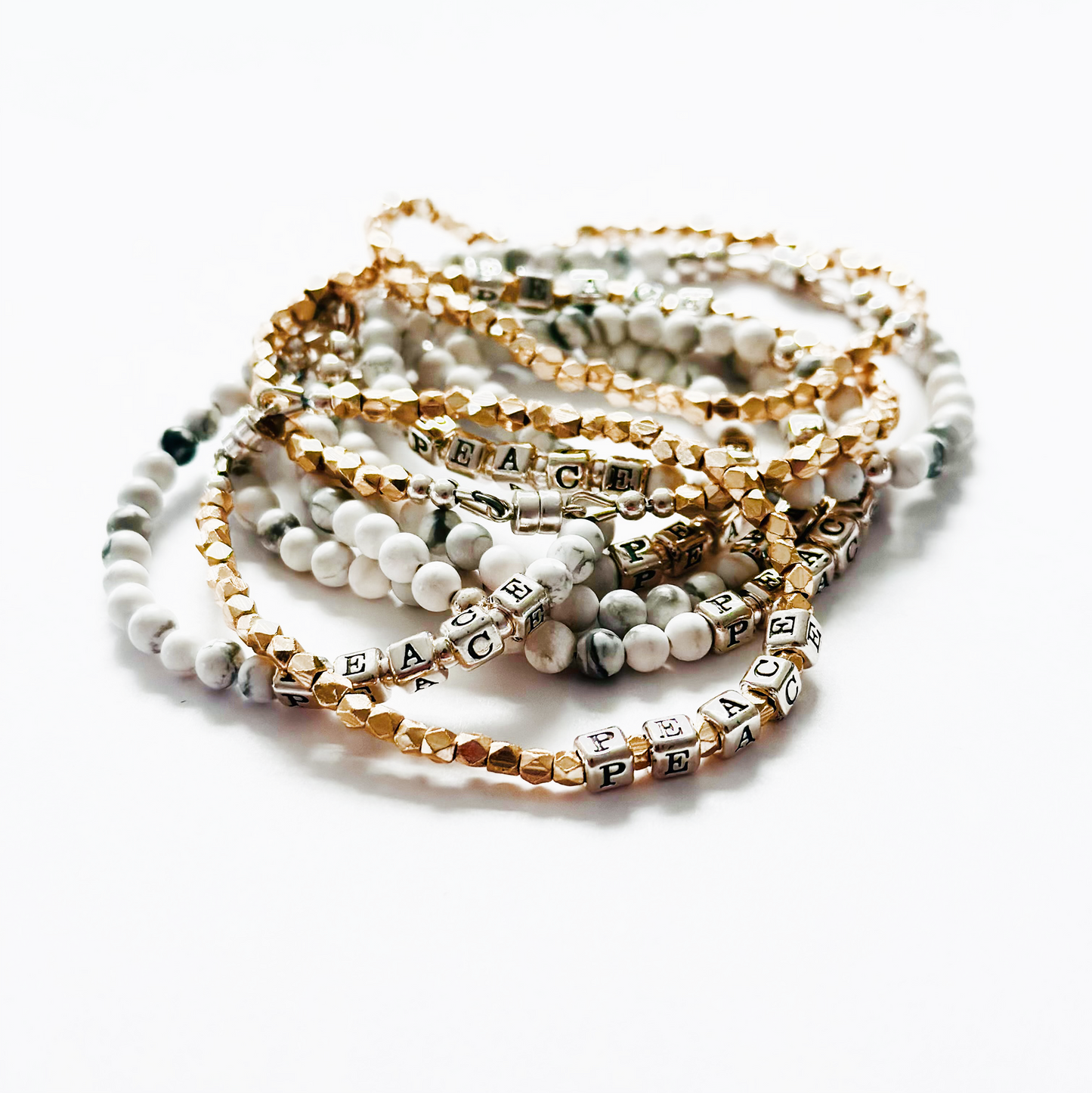 Peace stacking bracelets in sterling silver and gold and gemstones