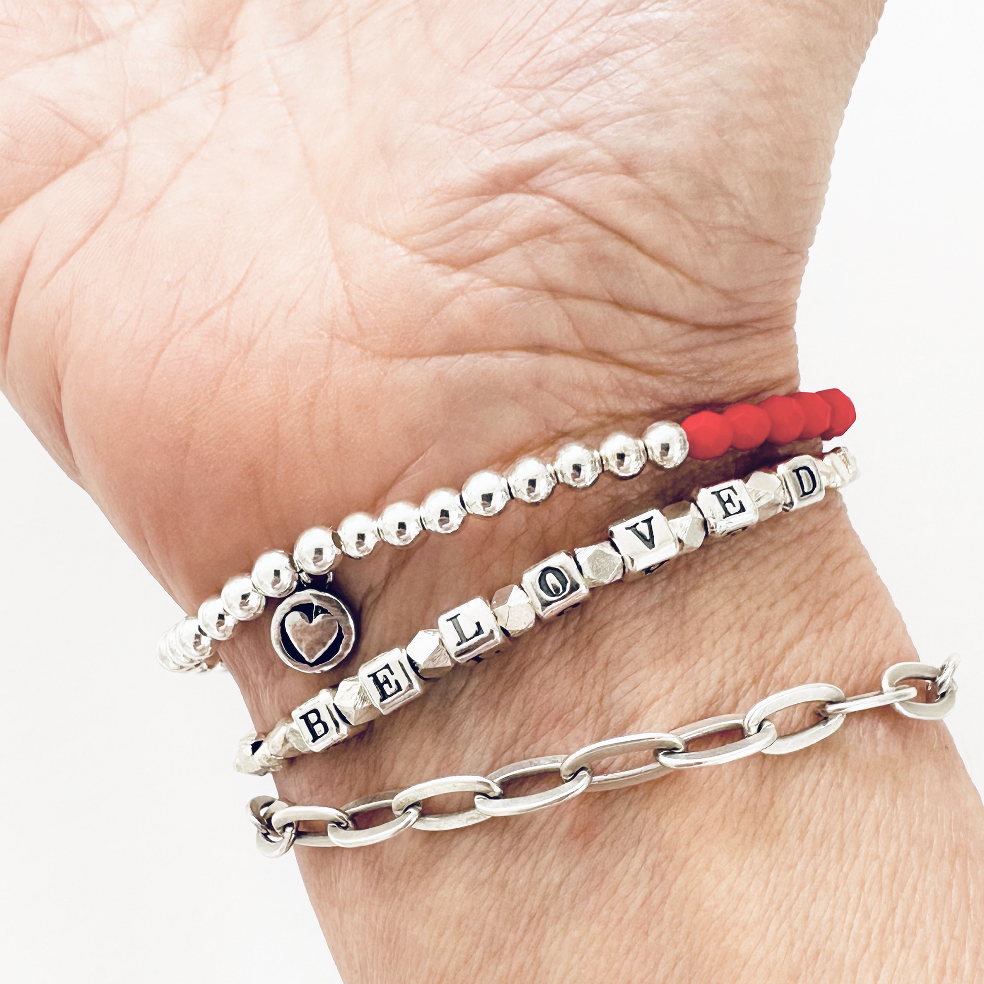 Beloved Love Bracelet in sterling silver and red beaded bracelet, shown on woman's wrist